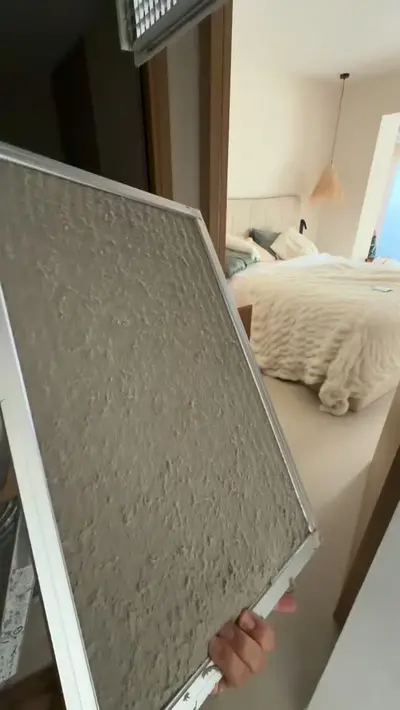Filtre de climatisation couvert de poussière, tenu devant une chambre