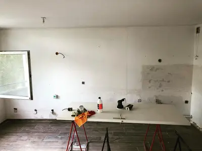Pièce vide avant la pose d’une cuisine, arrivées d’eau visibles au mur