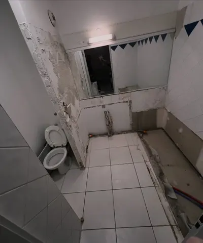 Même salle de bain pendant les travaux : baignoire et faïence déposées, sol et murs à nu